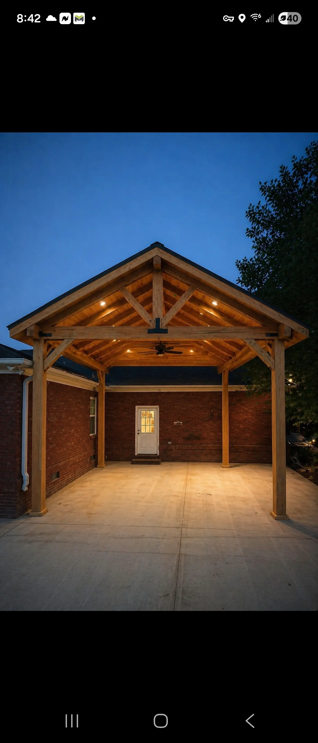 Illuminated timber frame patio cover with exposed beams and truss details at dusk