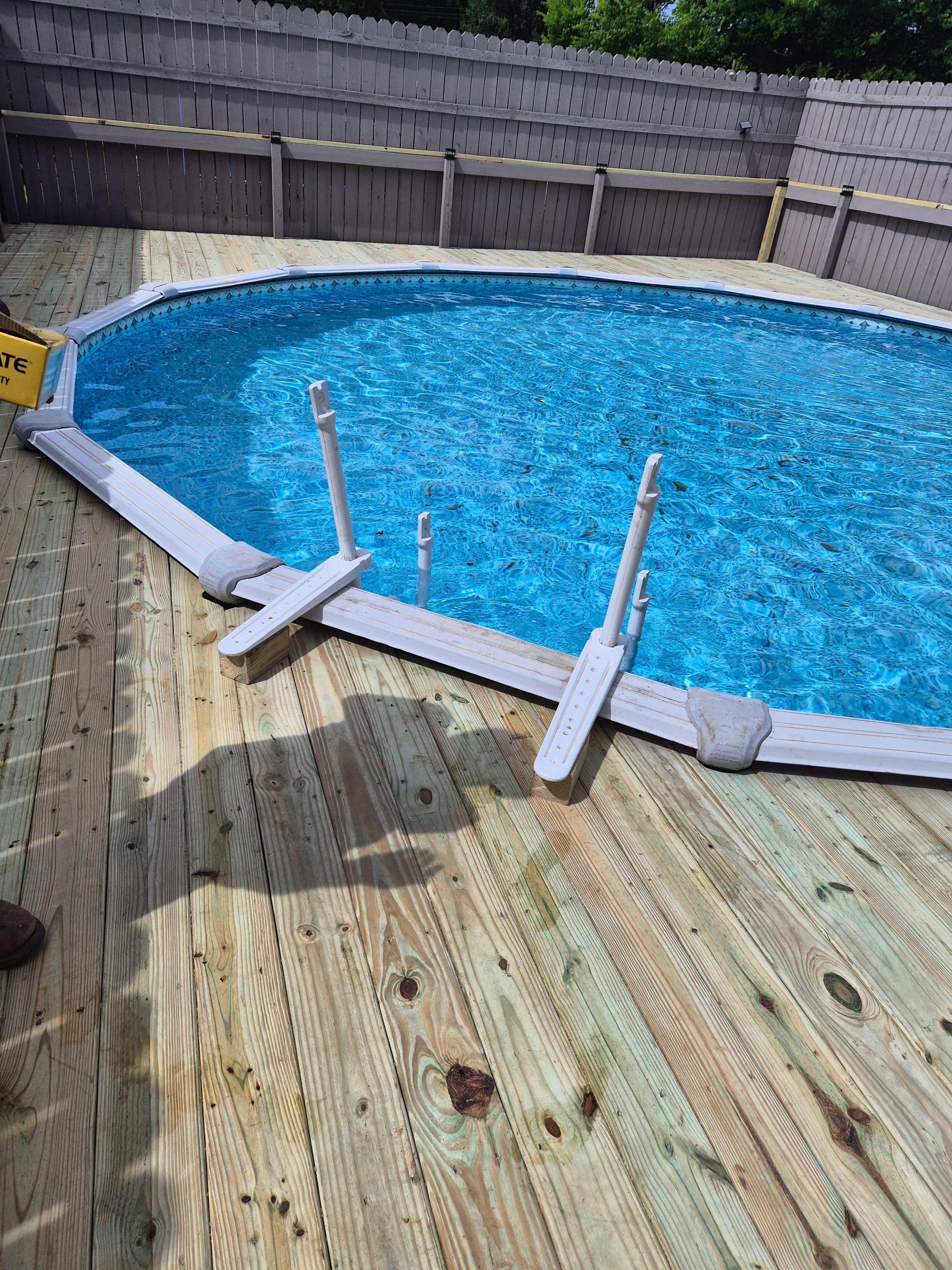 Above-ground pool with blue vinyl liner installed on wooden deck with metal frame supports